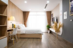 A modern minimalist bedroom with natural light, featuring cozy decor and wooden accents.